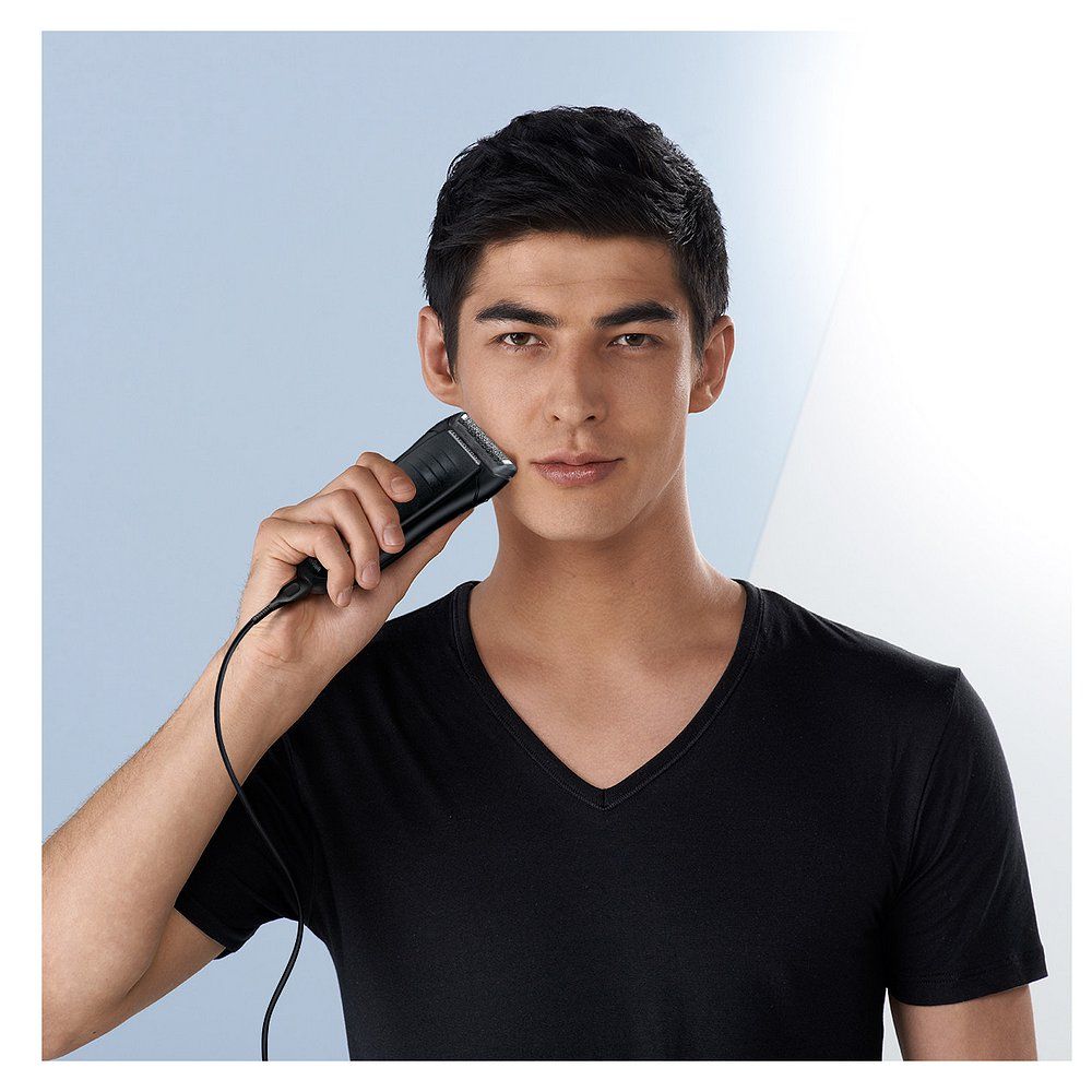 Homme utilisant un rasoir électrique Braun Series 1 pour se raser. L'appareil est connecté au câble de chargement.