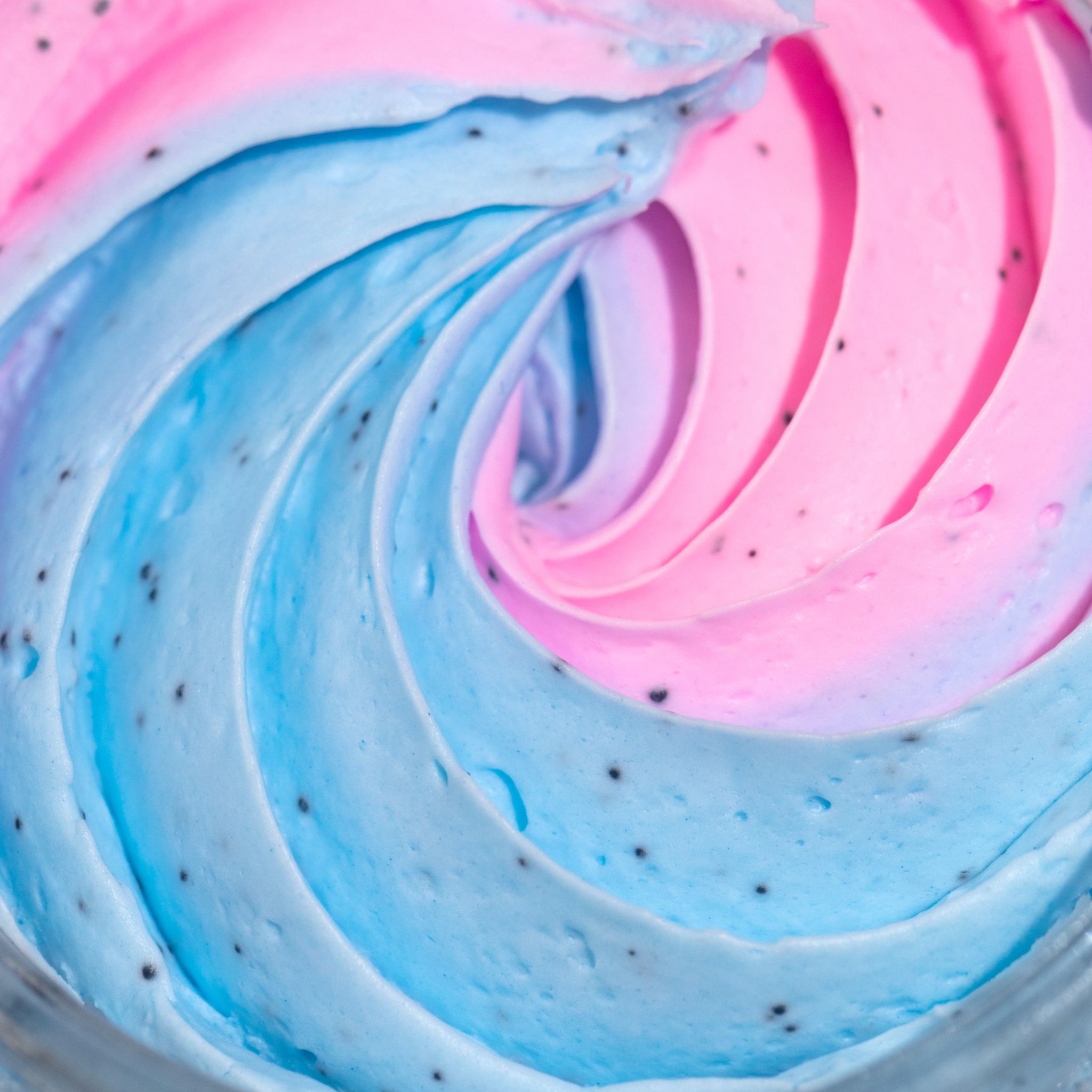 Close-up van roze en blauw wervelend product met kleine zwarte puntjes.