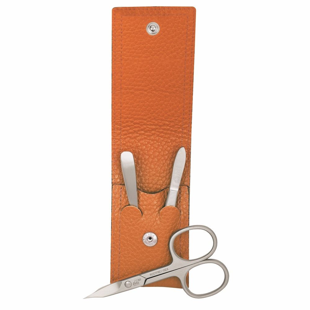 Étui en cuir orange avec trois instruments de manucure en acier inoxydable : ciseaux, pince à épiler, lime à ongles.