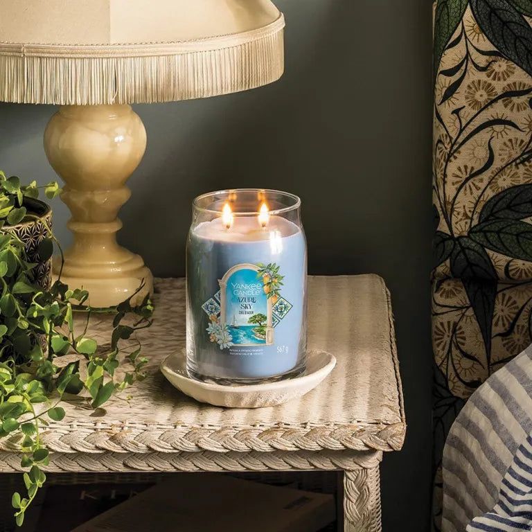 Blauwe Yankee Candle Azur Sky Signature Grand Pot op een nachtkastje. Twee lonten. Opschrift op etiket.