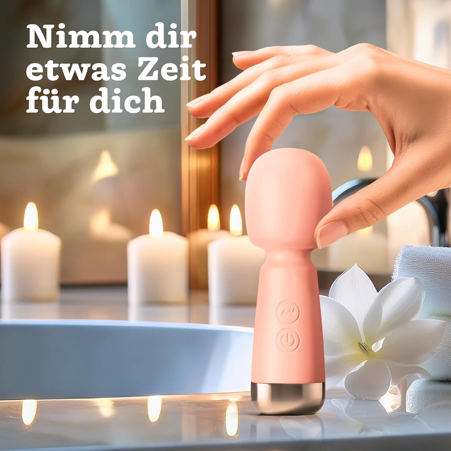 Main tenant un mini vibromasseur rose devant des bougies et une fleur de magnolia.