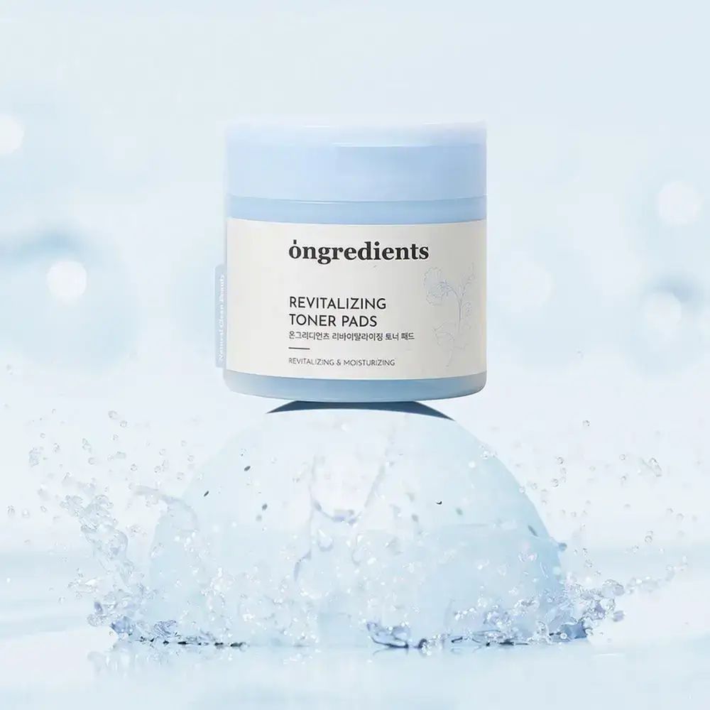 Blauw-witte pot "ongredients Revitalizing Toner Pads" op blauw voetstuk, omringd door water. Productpresentatie.