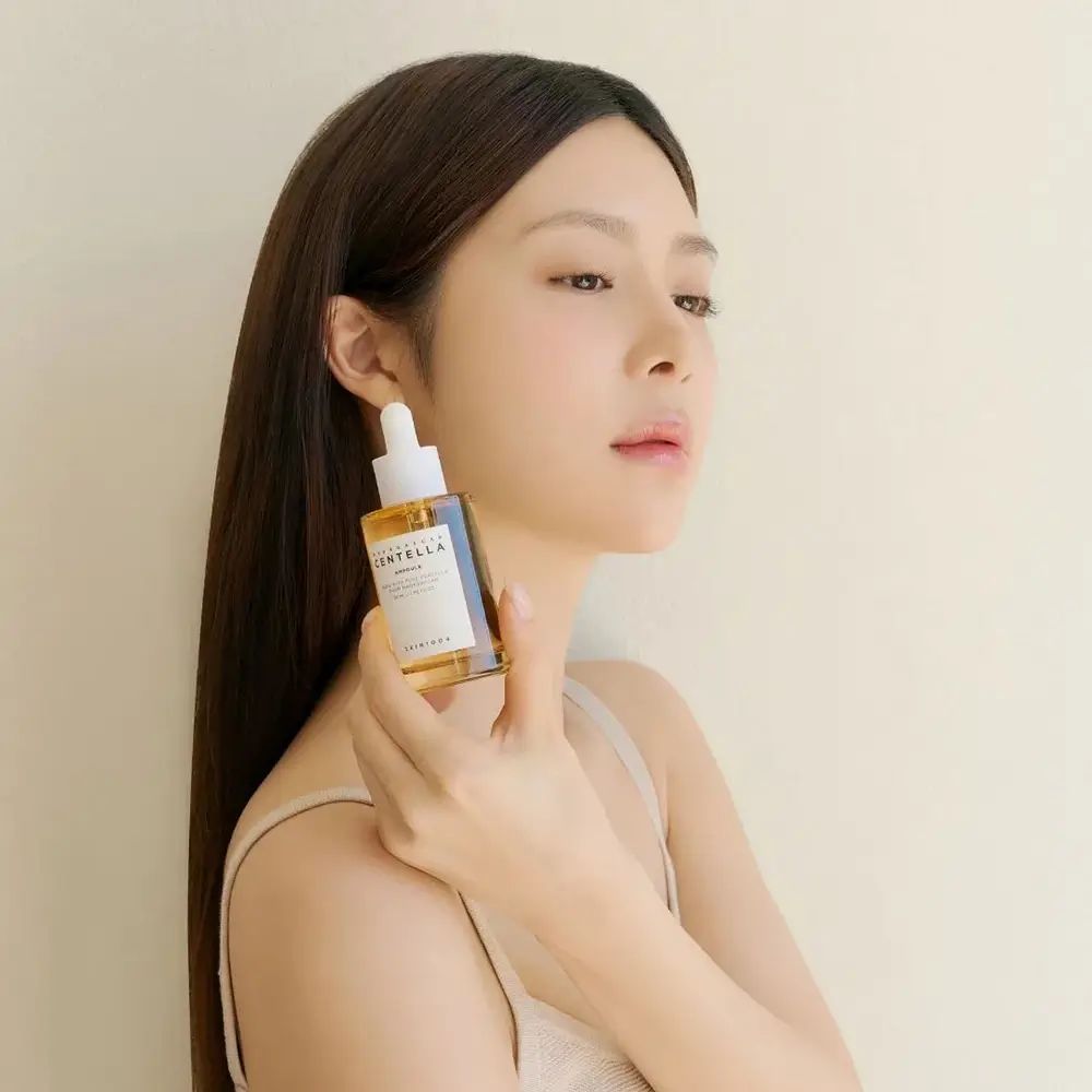 Femme tenant une ampoule SKIN1004 Madagascar Centella. Flacon brun, pipette blanche.