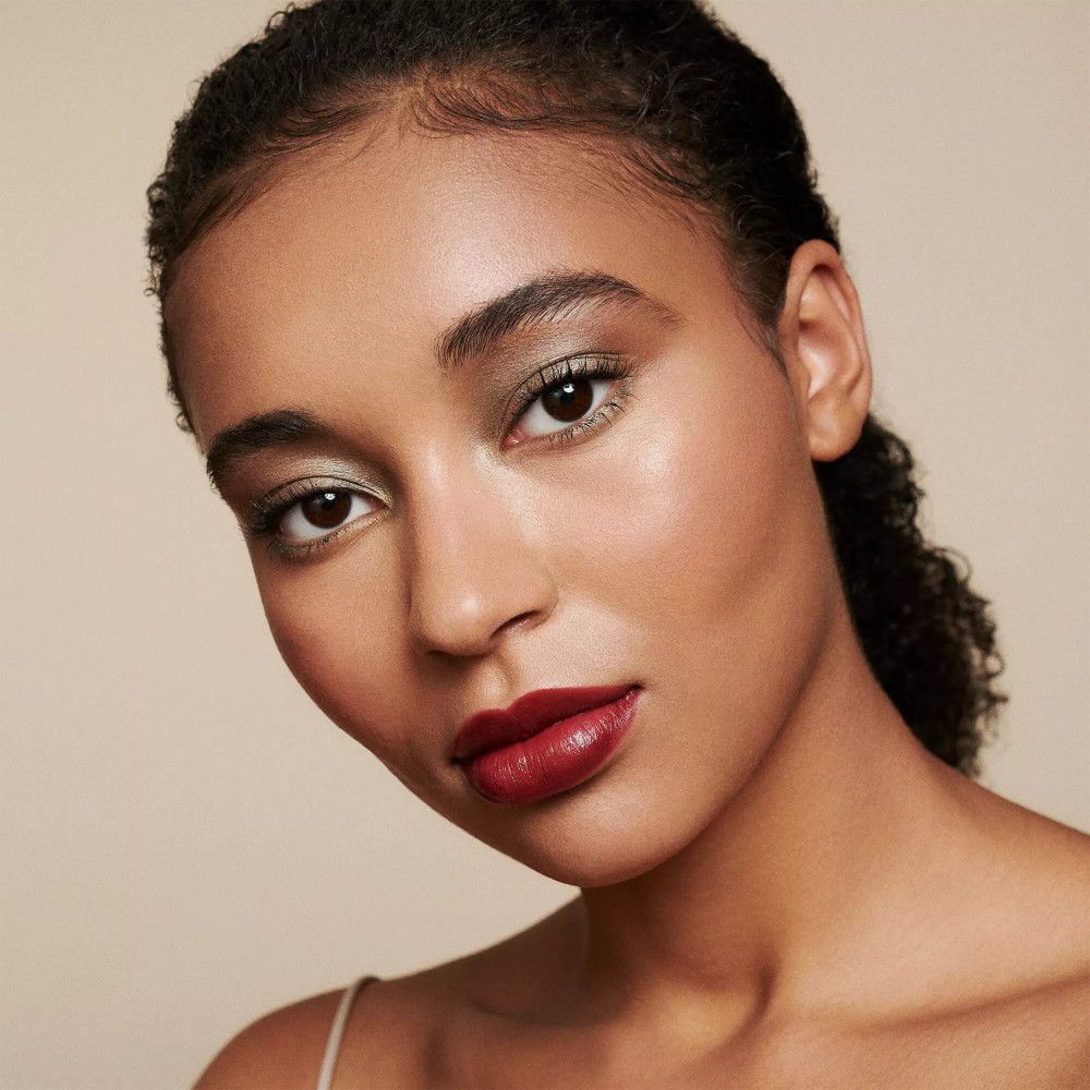 Portrait d'une femme maquillée. Fard à paupières, rouge à lèvres. Teint clair. Fond : beige.