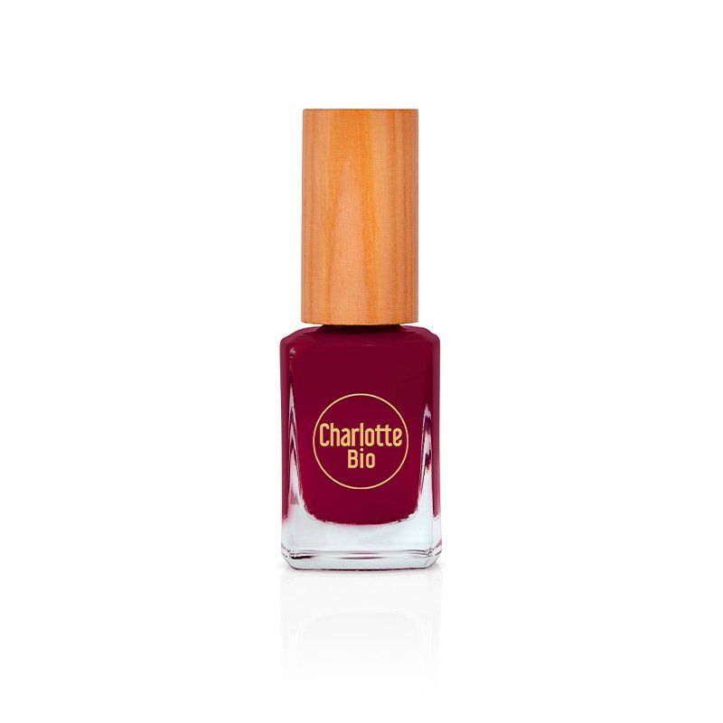 Flacon de vernis à ongles avec bouchon en bois. Vernis rouge foncé. "Charlotte Bio" est inscrit sur le flacon.