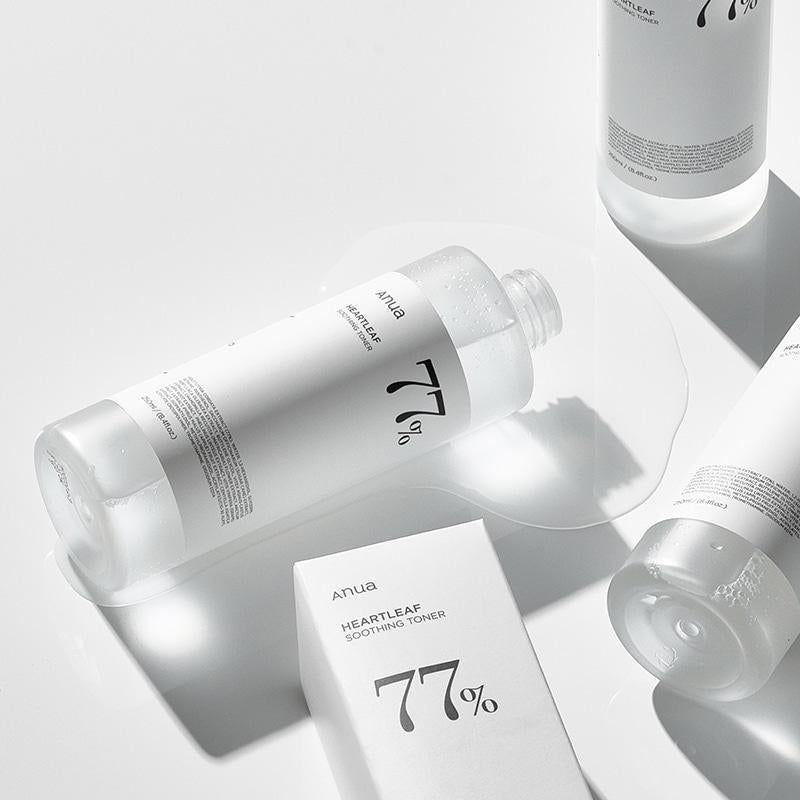 Meerdere witte flessen met heldere vloeistof op witte ondergrond. Eén fles ligt, vloeistof ernaast.