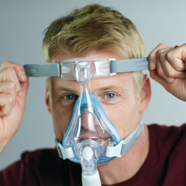 Homme avec masque CPAP Philips Amara SE Gel Full : ajustement de l'attache de tête.