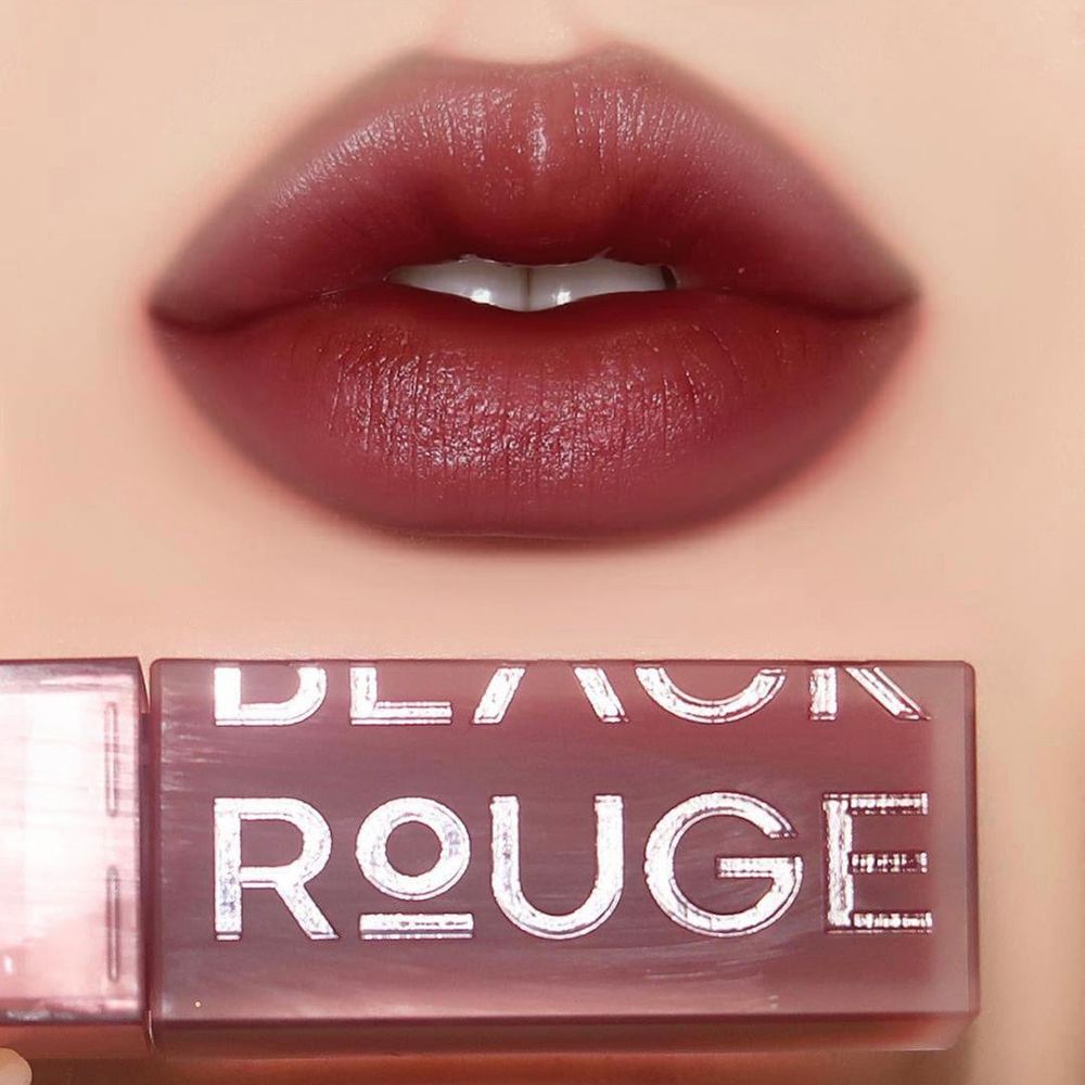 Lèvres maquillées avec un gloss rouge foncé. Le nom "ROUGE" et "BLACK ROUGE" est visible sur le packaging.