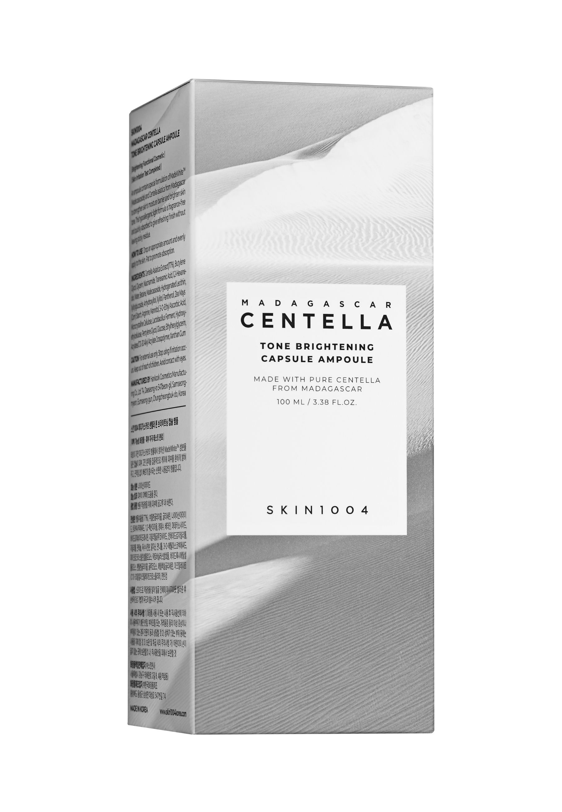 Kartonnen verpakking met productinformatie. Opschrift: MADAGASCAR CENTELLA, Tone Brightening Capsule Ampoule. SKIN1004 logo.