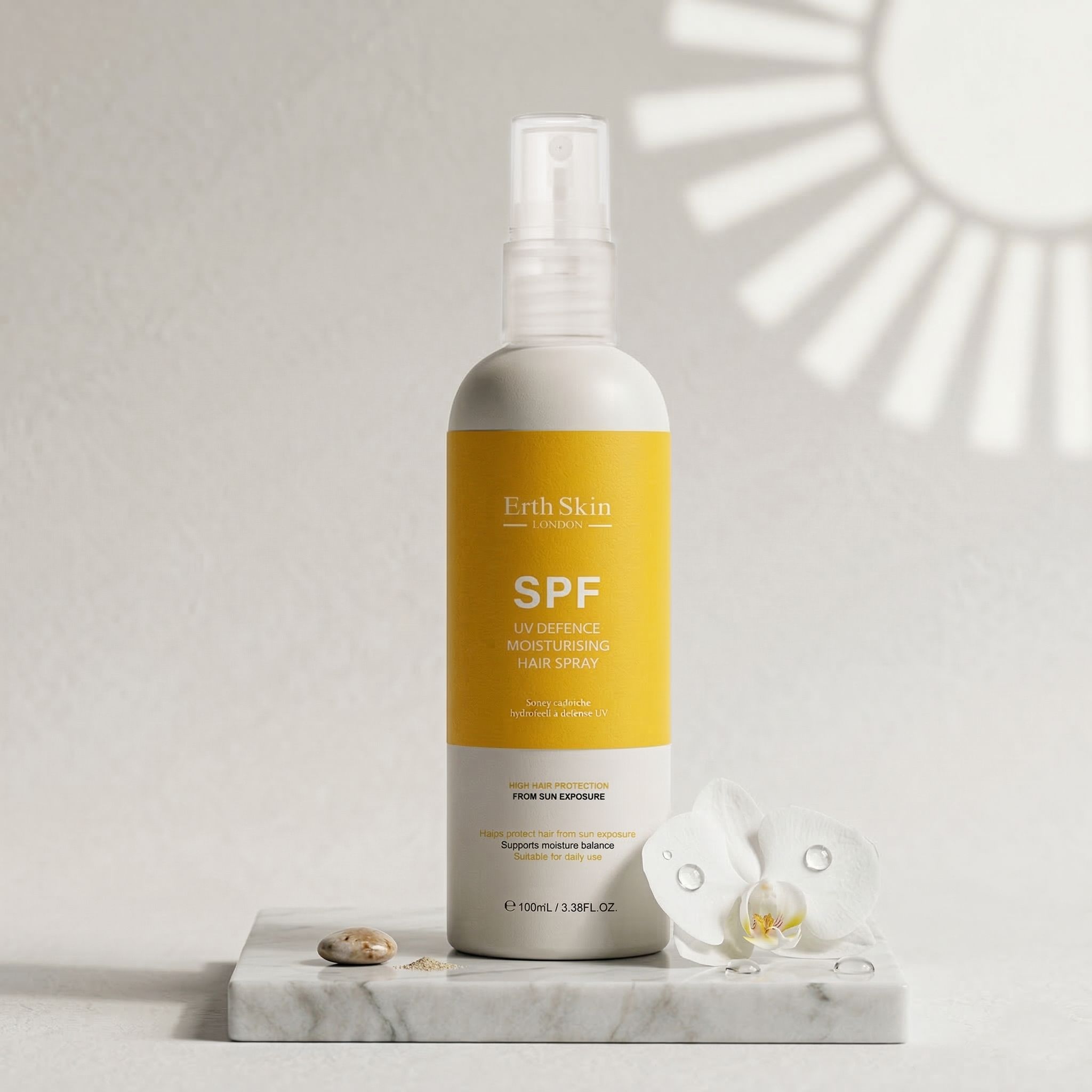 Flacon de spray capillaire avec étiquette jaune. Inscription : SPF. ErthSkin London. Sur une plaque de marbre avec fleur et pierre.
