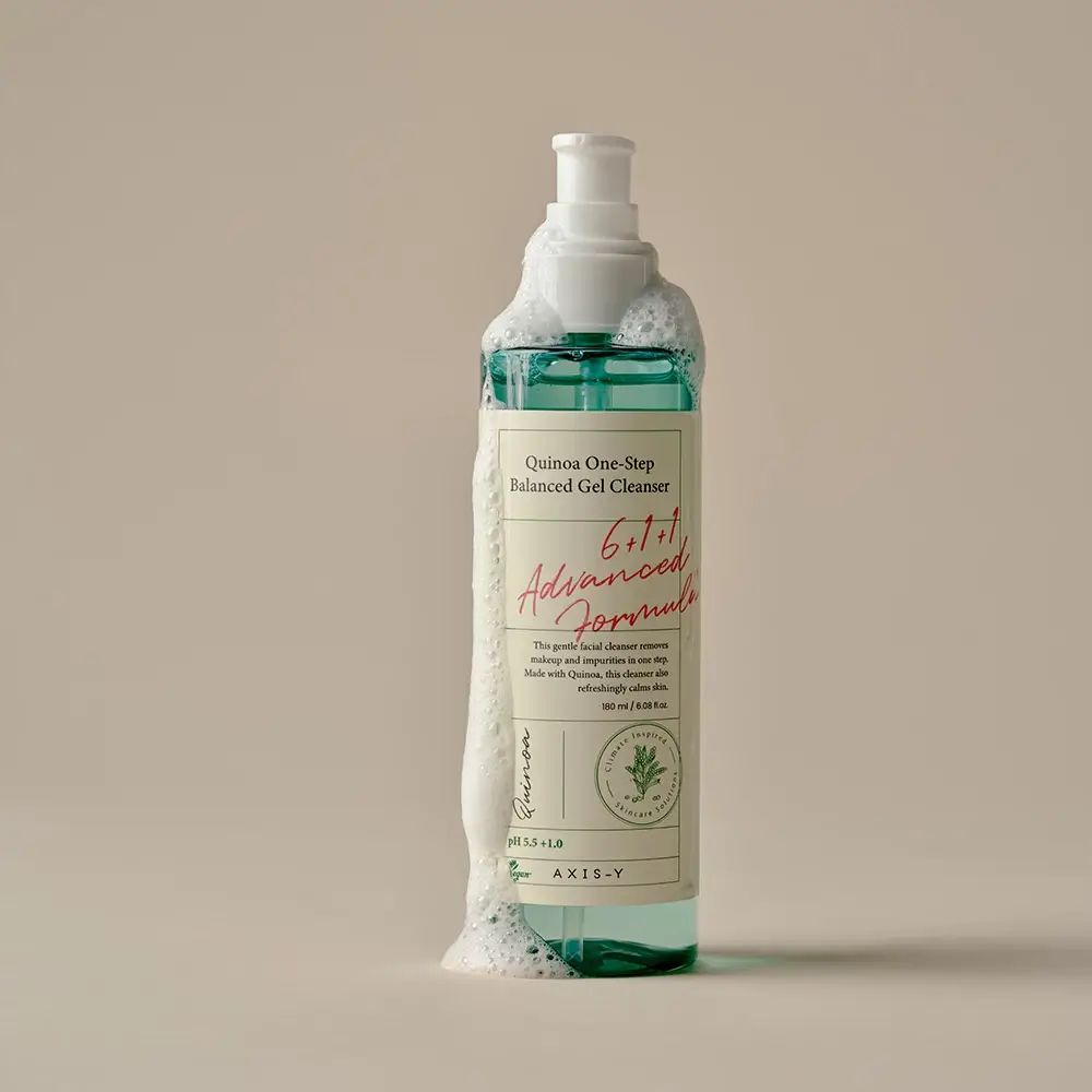 Fles bedekt met schuim. Opschrift: Quinoa One-Step Balanced Gel Cleanser. Roze tekst: 6+1+1 Advanced Formula.