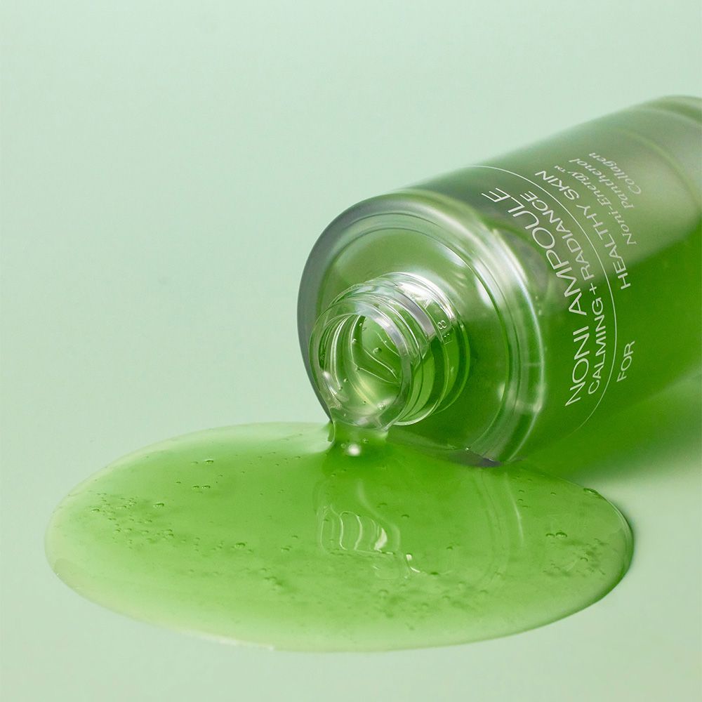 Liquide vert versé d'une ampoule Celimax Noni Energy renversée.