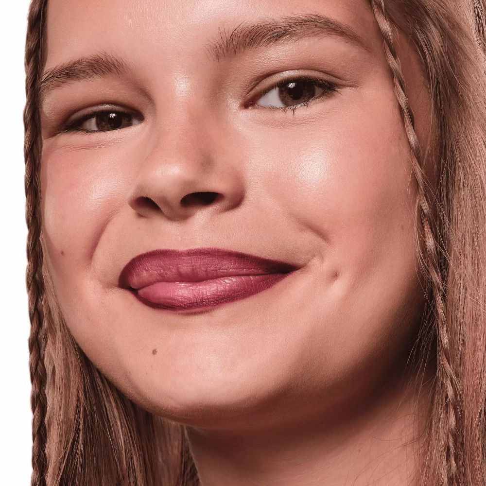 Close-up van een lachend meisje met vlechten. Lippen geaccentueerd met roze lippenstift.