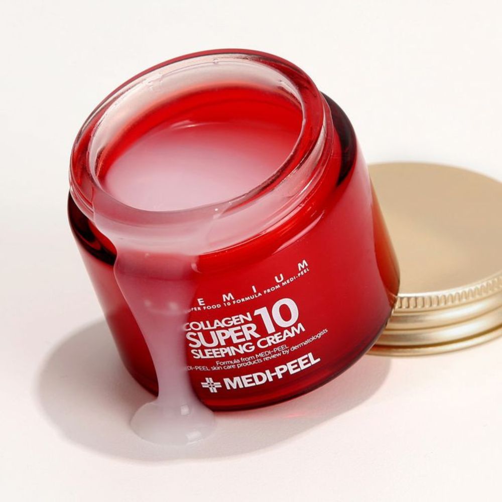 Pot de crème en verre rouge ouvert avec couvercle doré, montrant une crème blanche débordant du bord.