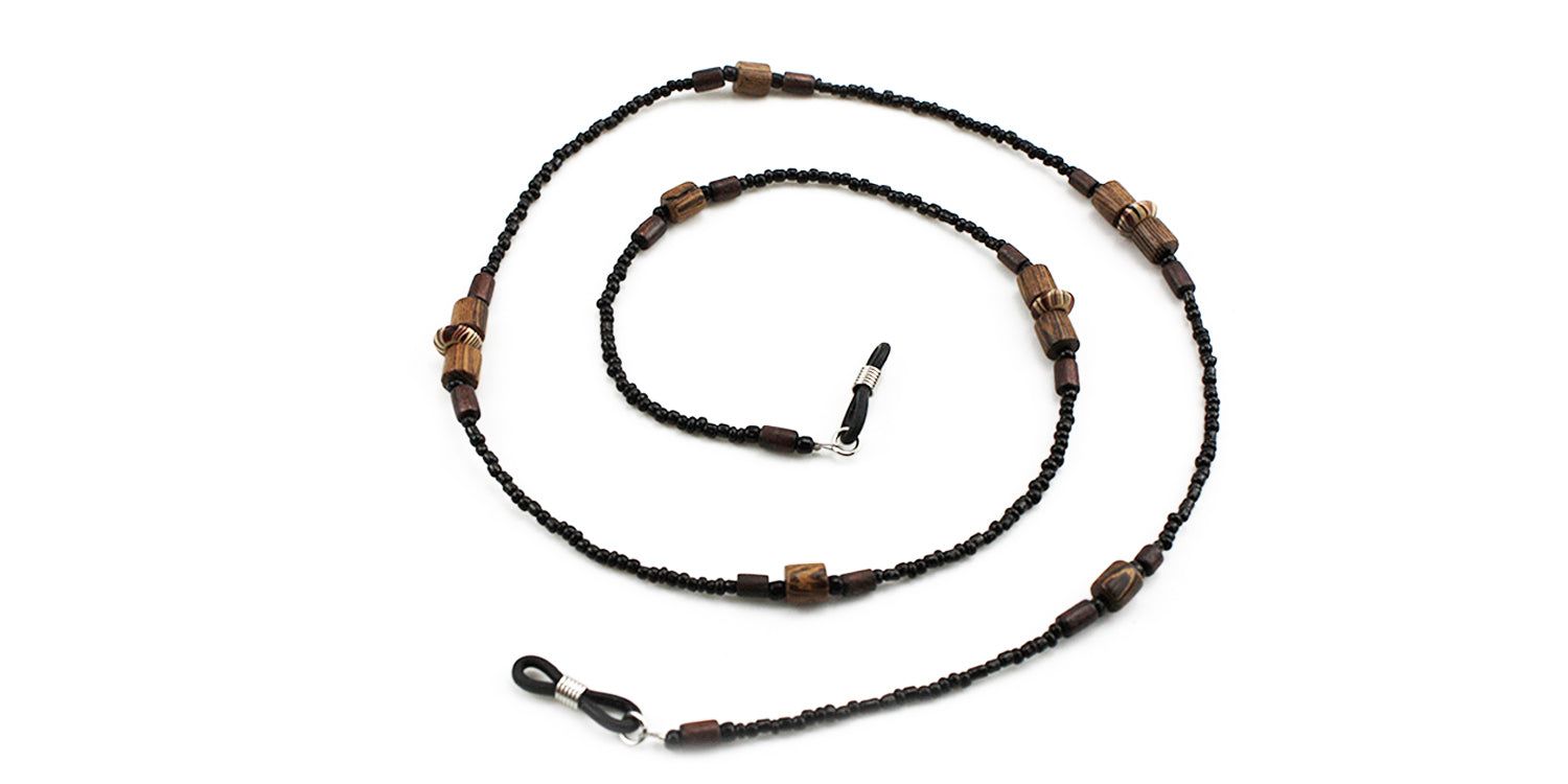 Cordon à lunettes noir avec perles et perles en bois. Attaches métalliques pour lunettes. Fond blanc.