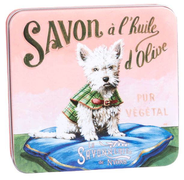 Gesloten metalen doos met afbeelding van witte terriër op blauw kussen. Opschrift 'Savon à l'huile d'olive'.