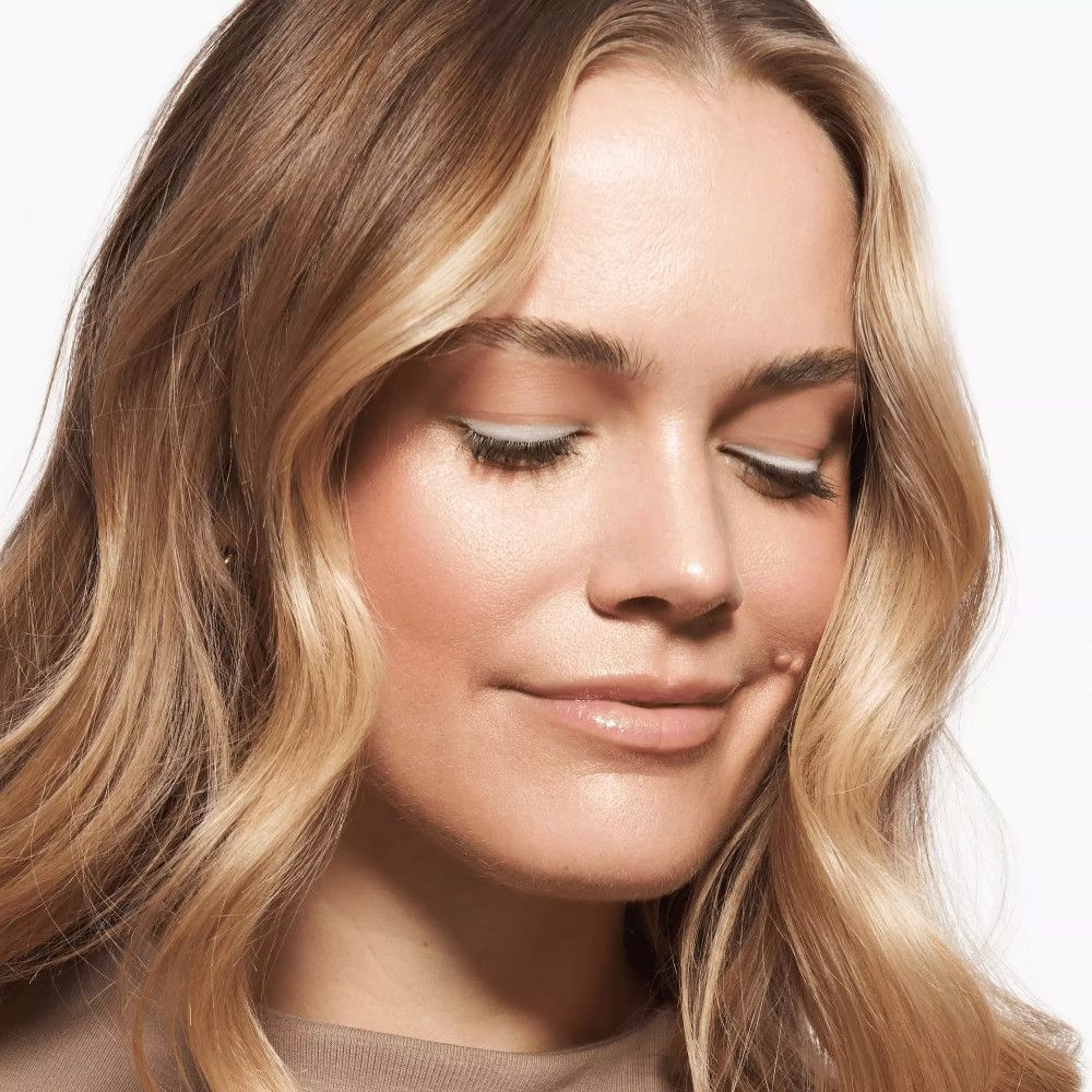 Femme aux cheveux blonds et aux yeux fermés. Baume à lèvres appliqué.