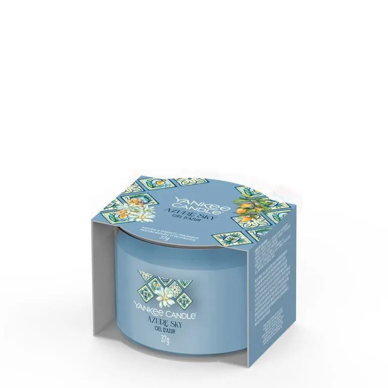 Bougie bleu clair dans emballage. Inscription: Yankee Candle Azure Sky, 37g. Emballage à motifs.