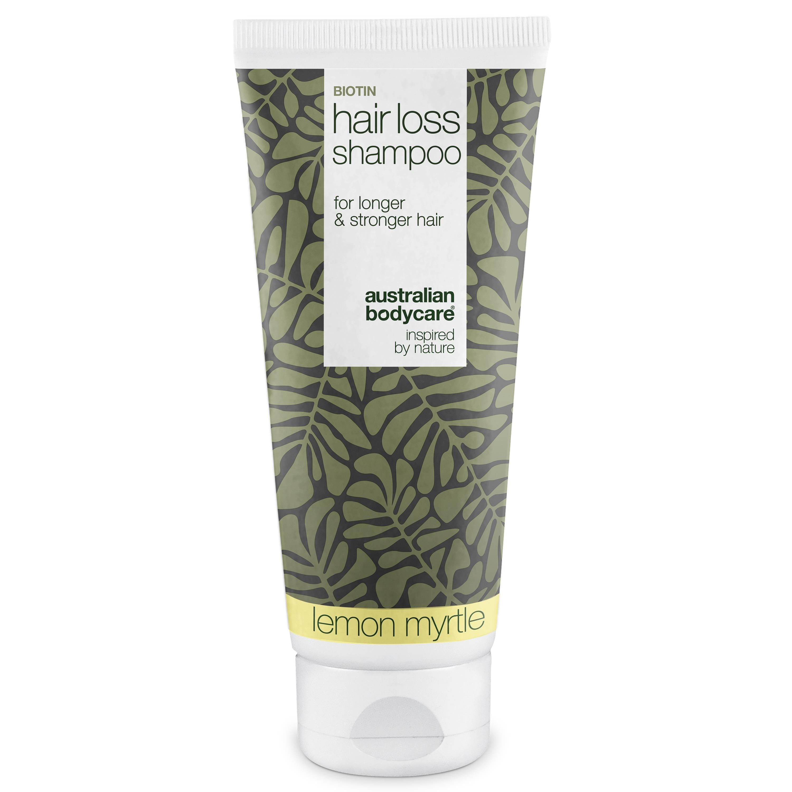 Tube de shampooing Biotin Hair Loss. Design vert et blanc avec motif de feuilles. Texte: Hair Loss Shampoo, Lemon Myrtle.