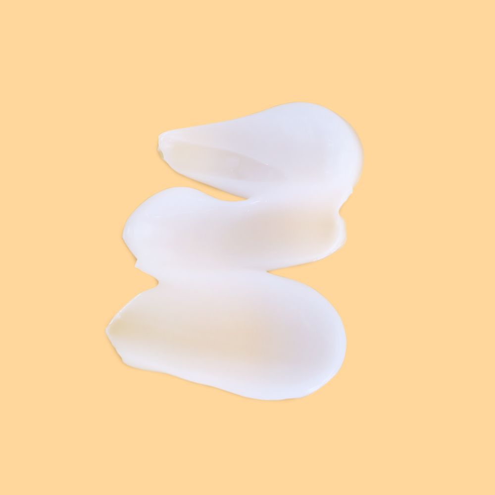 Trois traits de crème crème sur fond jaune clair.