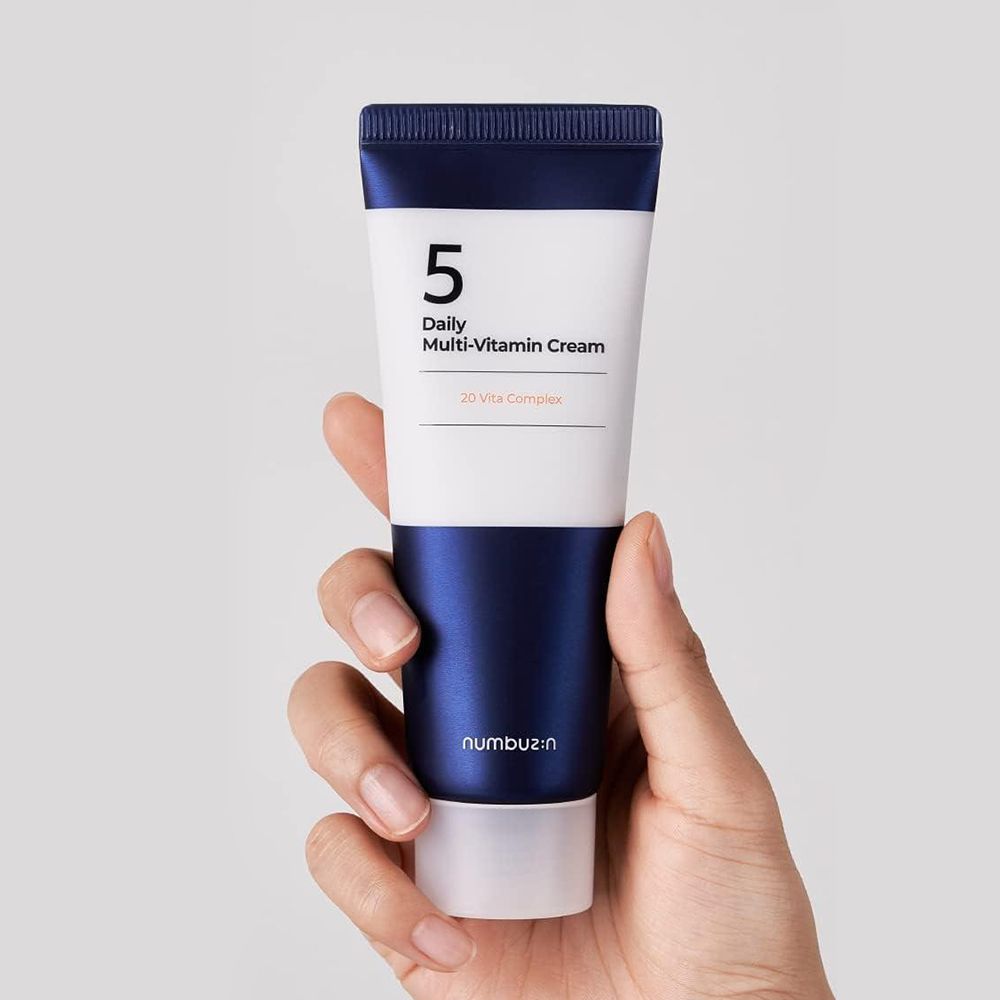 Crèmetube in een hand. Opschrift: 5, Daily Multi-Vitamin Cream, 20 Vita Complex. Merk: numbuz:n.