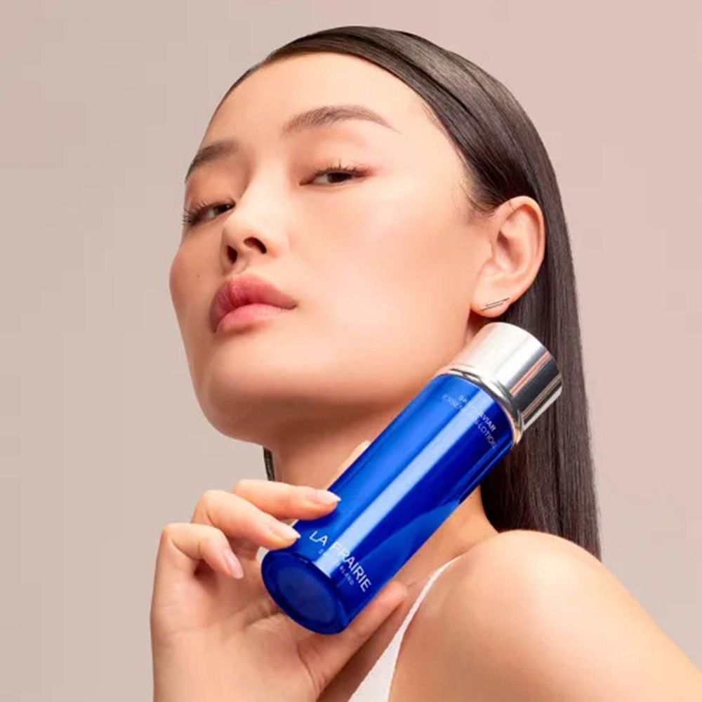 Femme tenant un flacon La Prairie Skin Caviar Essence-in-Lotion.