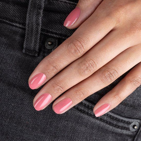Main avec ongles vernis en rose. La main est posée sur un jean.