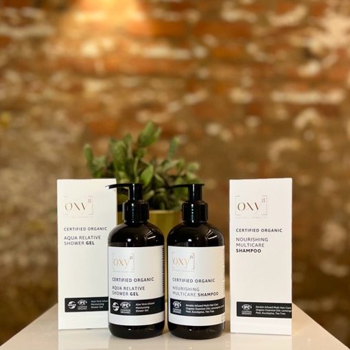 Twee flessen met pompdeksel en twee kartonnen dozen. Op de etiketten staat "Oxy8" en "Certified Organic".