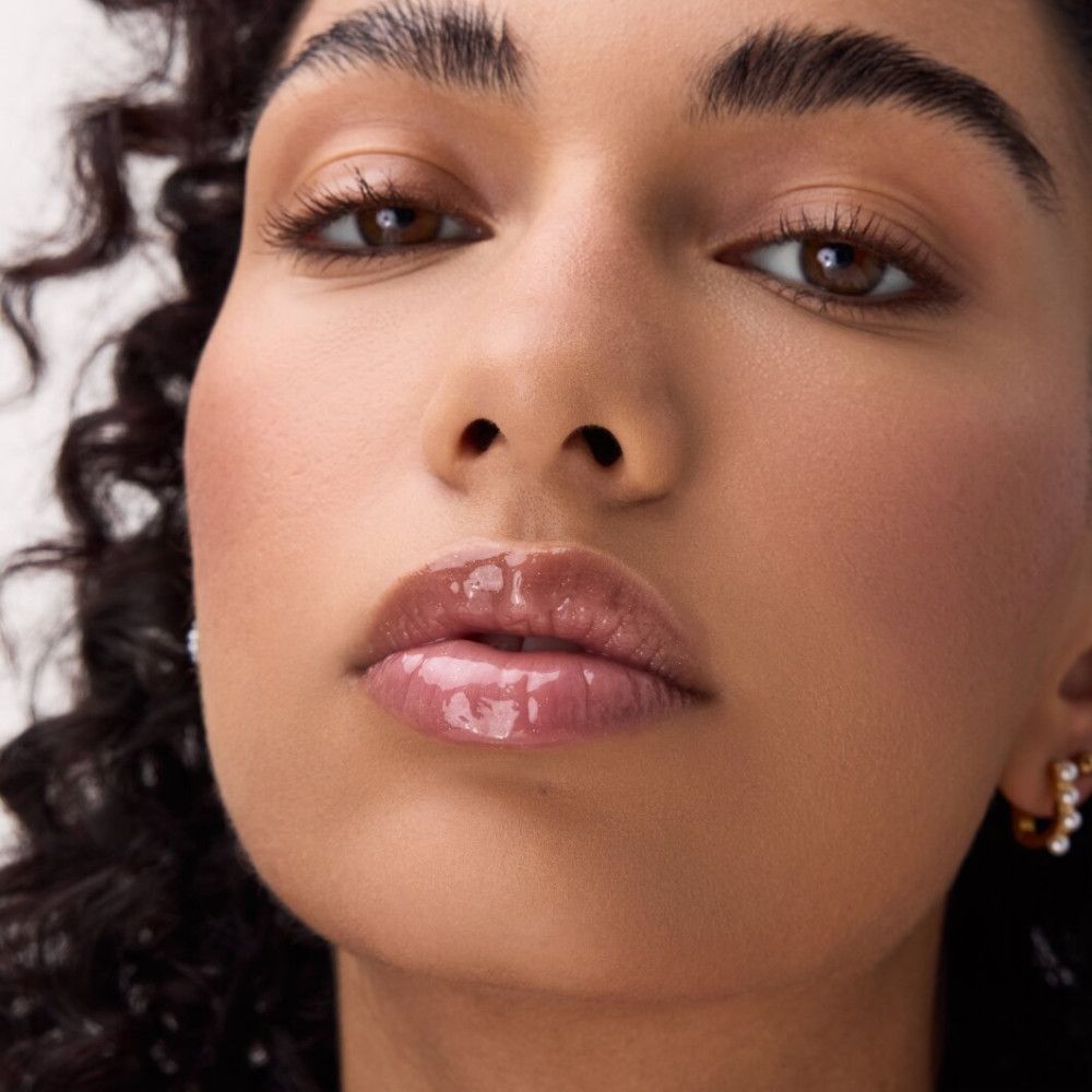 Close-up van een gezicht met glanzende lippen. Lipelixer op de lippen.