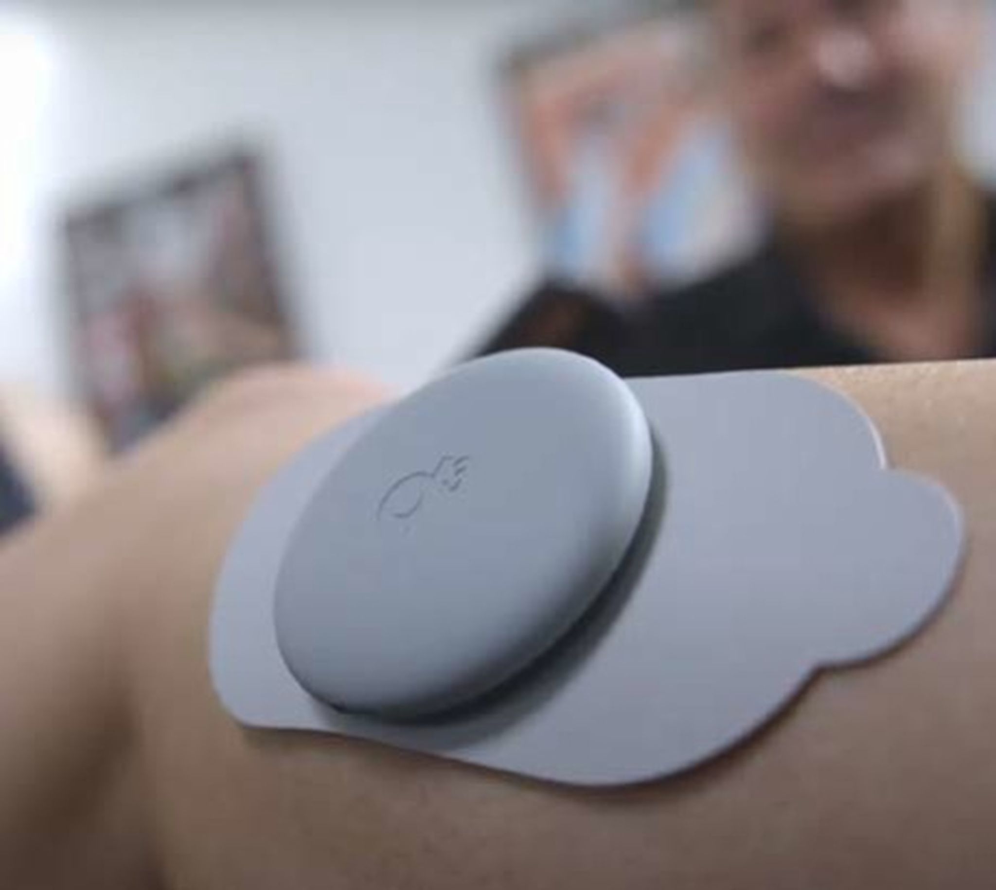 Een grijze spierstimulator op een pad, aangebracht op de huid.