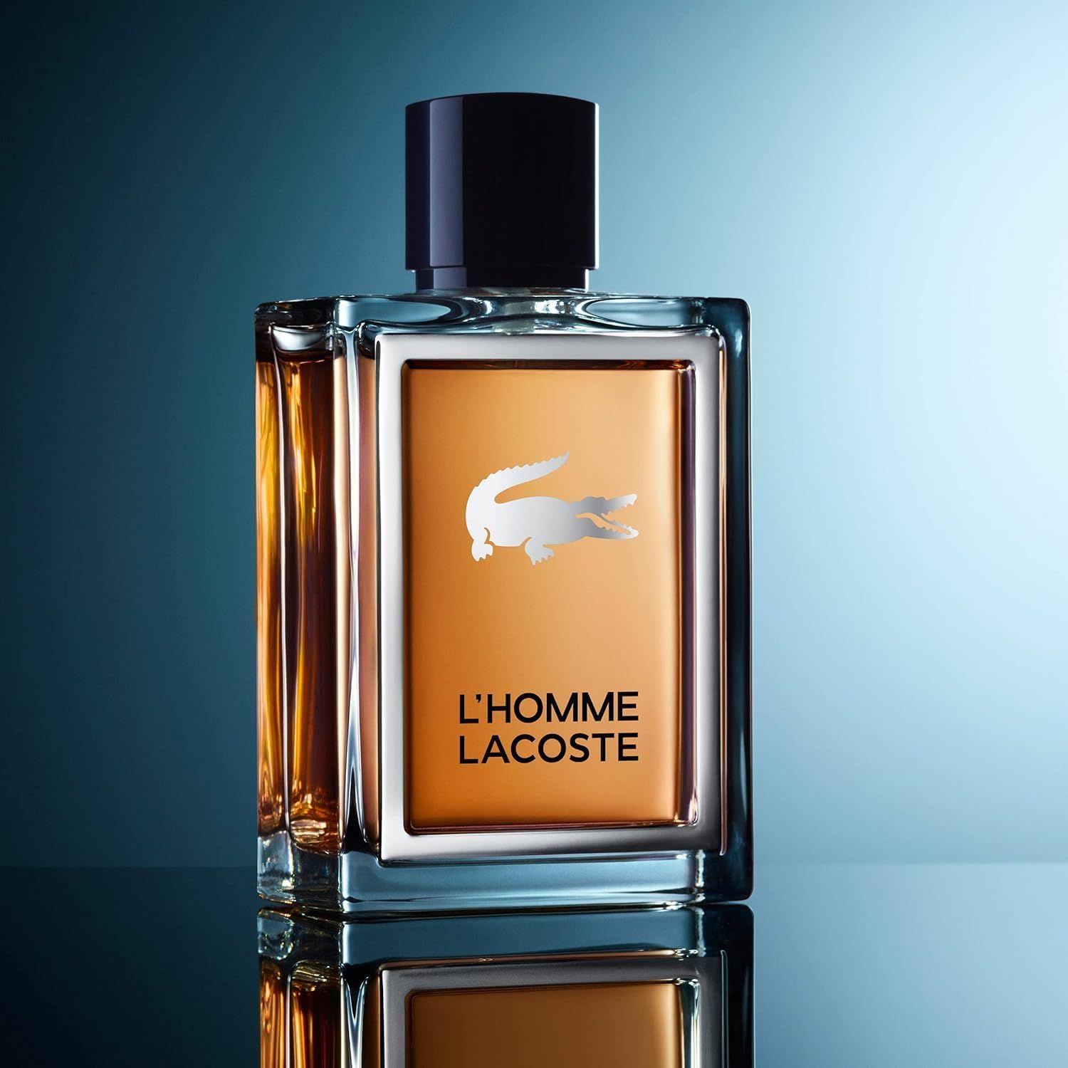 Flacon Lacoste L'Homme Eau de Toilette sur surface réfléchissante, fond bleu.
