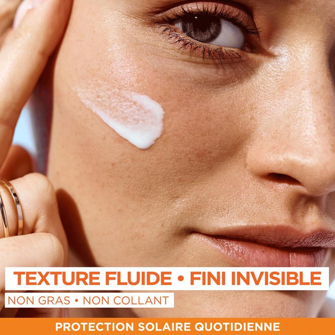 Une crème blanche est appliquée sur la joue d'une femme. Texte : "Texture fluide, fini invisible, non gras, non collant, Protection solaire quotidienne."