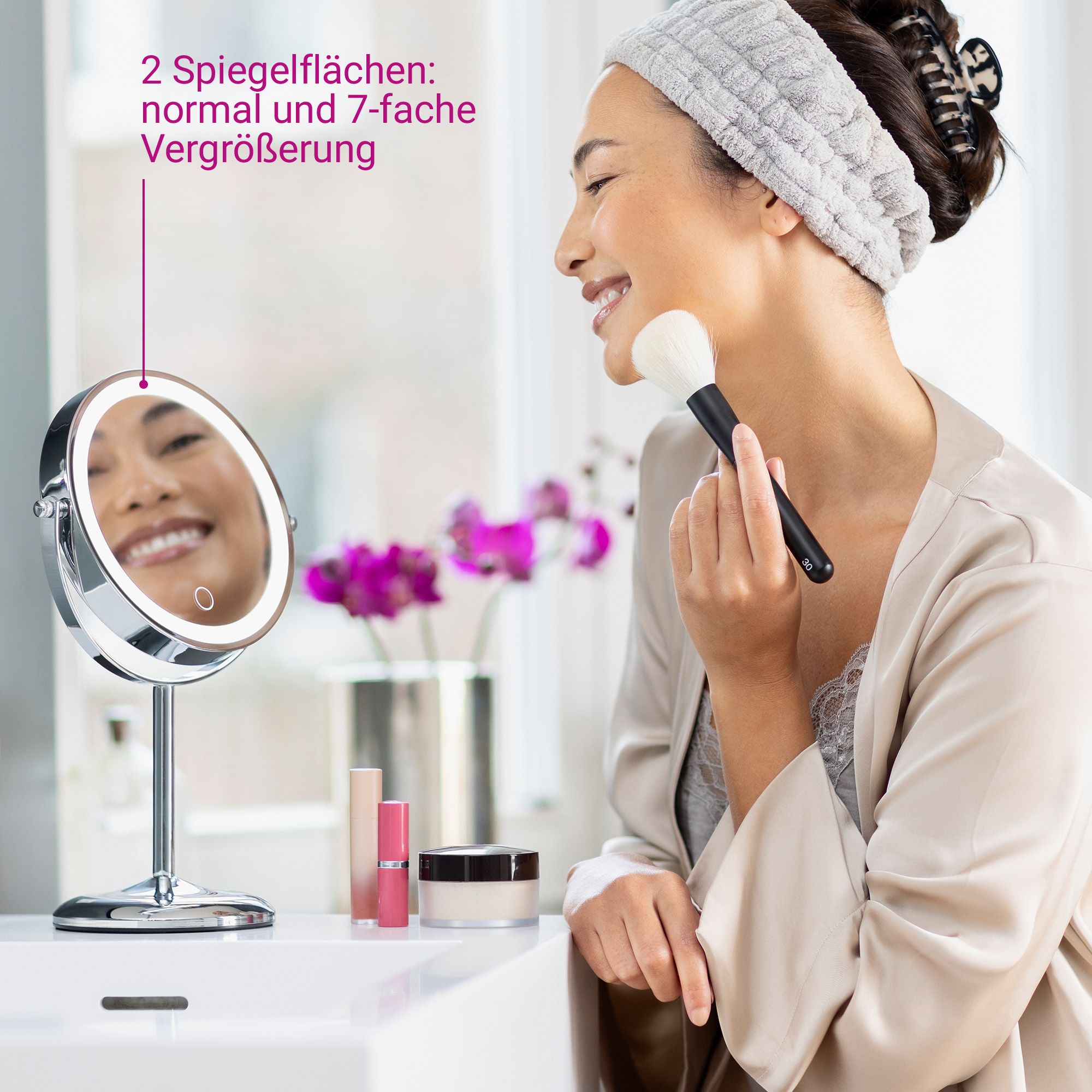 Femme se maquillant avec pinceau devant un miroir cosmétique éclairé (grossissement 7x).