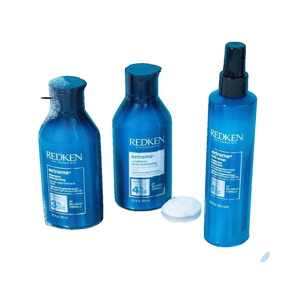 Drie blauwe flessen met zwarte doppen en etiketten. Eén fles heeft een verstuiver. Een wit pad ligt ernaast.