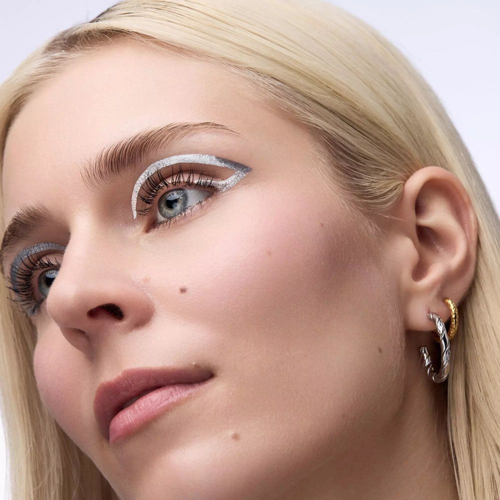 Portrait d'une femme aux cheveux blonds et au maquillage bleu. Eyeliner argenté appliqué.