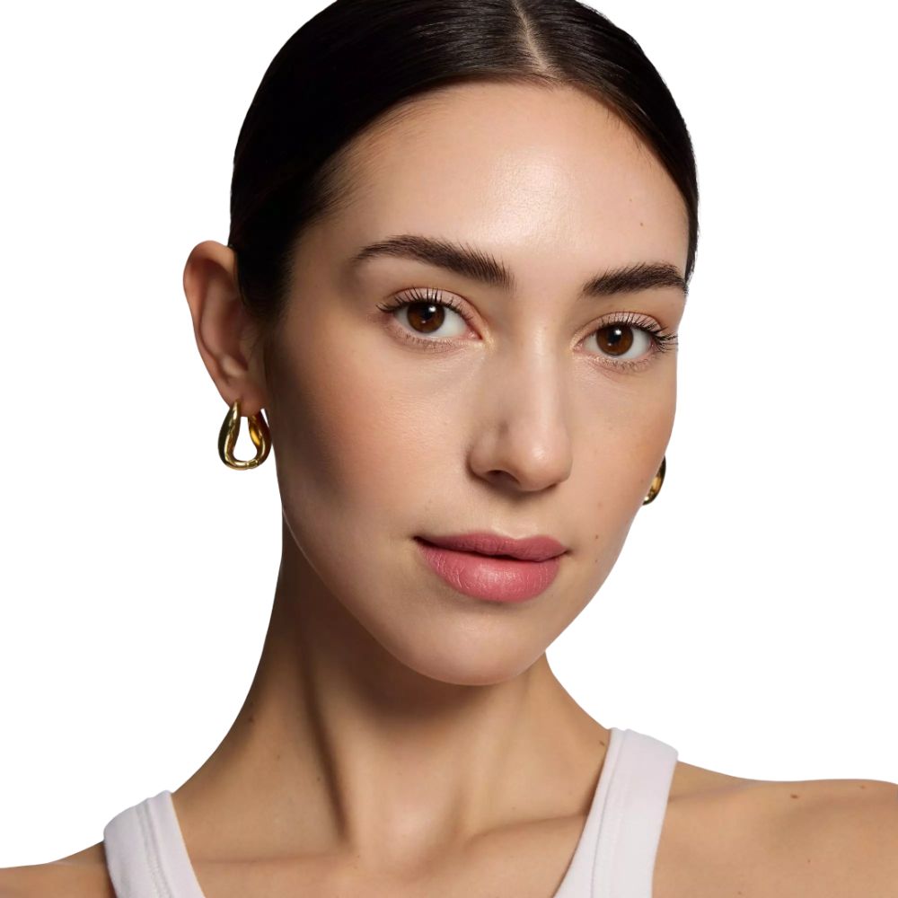 Portrait d'une femme aux cheveux châtain clair et aux boucles d'oreilles dorées. Elle porte du rouge à lèvres rose.