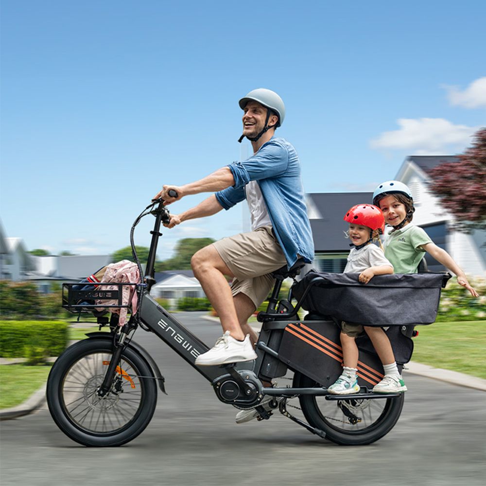 Man fietst op e-bike met twee kinderen in de bagagedrager. Merk ENGWE. Zwarte e-bike.