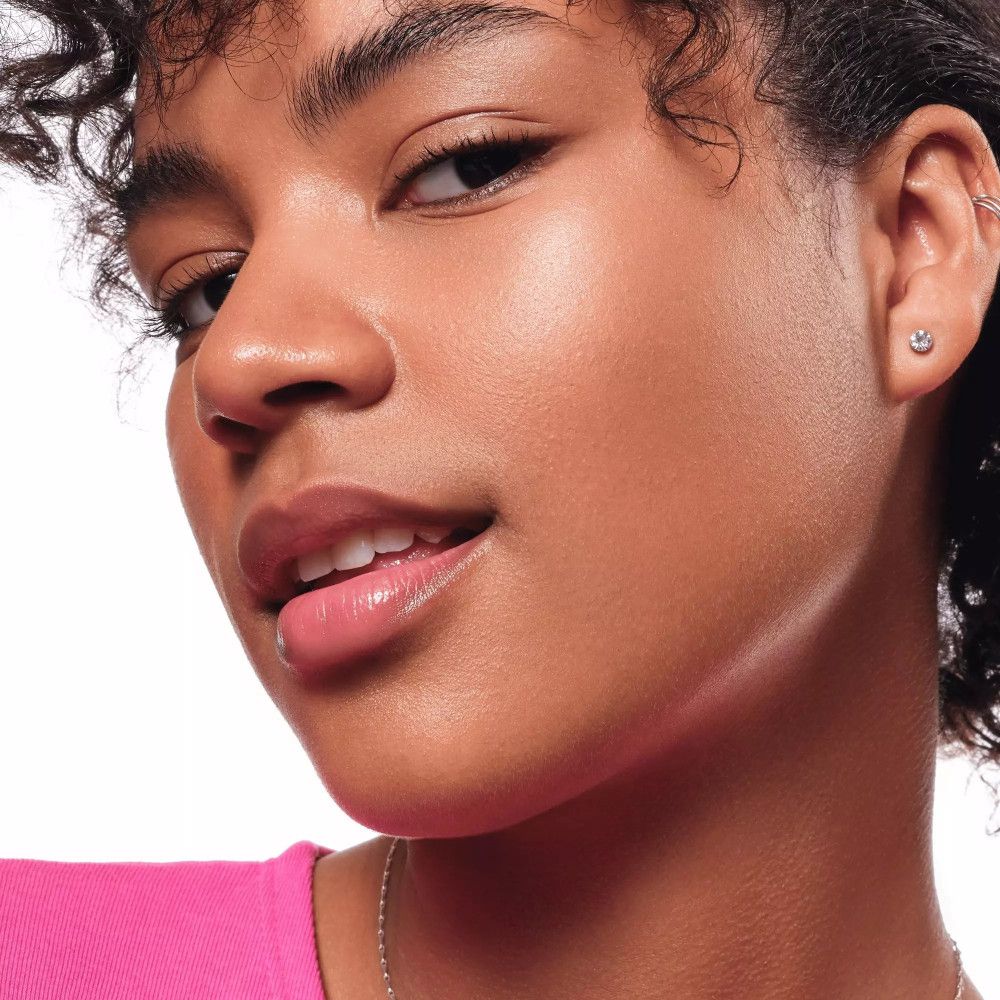 Close-up van een vrouw met gehighlighte huid. Ze draagt een roze top.