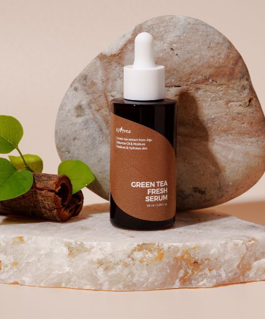 Flacon en verre brun avec sérum sur pierre. Étiquette avec nom du produit et texte. ISNTREE Green Tea Fresh Serum.