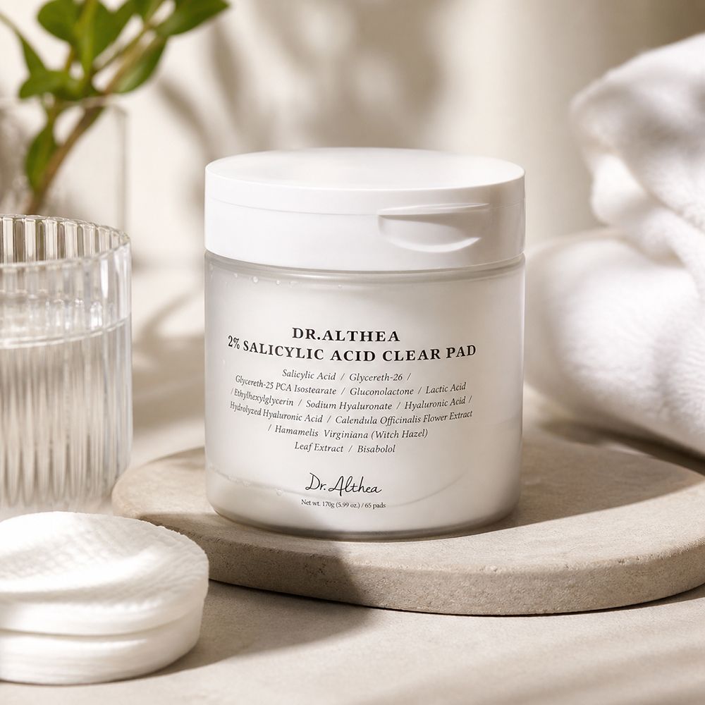 Dr. Althea 2% Salicylic Acid Clear Pad op een stenen plateau, naast wattenschijfjes en een glas.