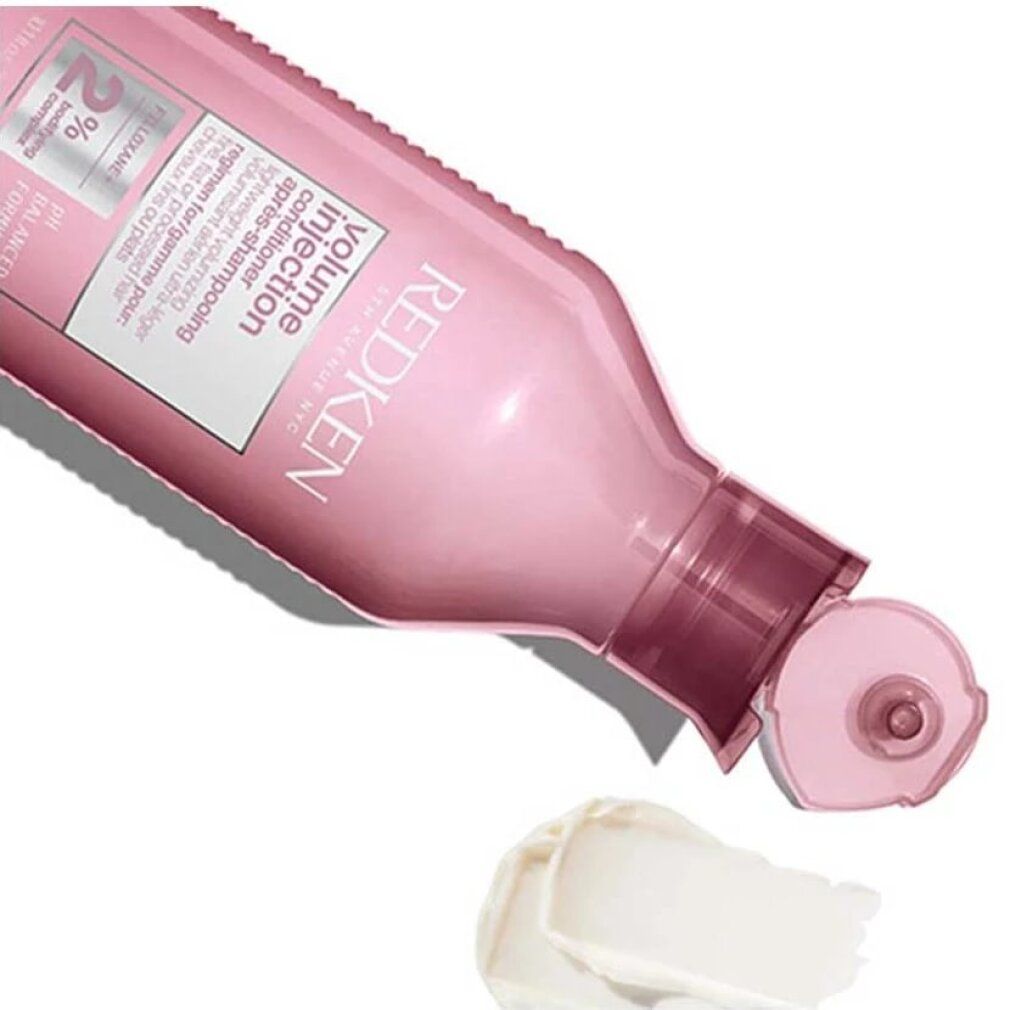 Flacon rose Redken Volume Injection Conditioner. Produit versé. Crème sur fond blanc.