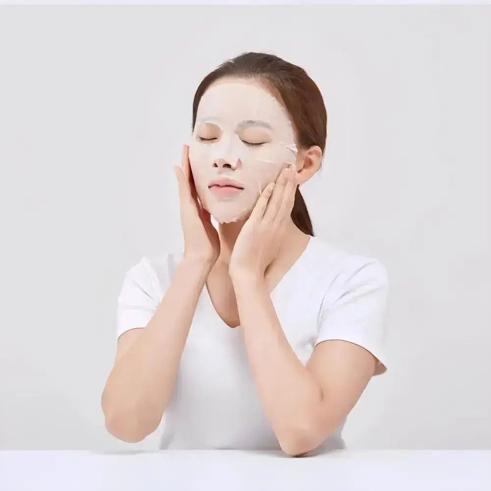 Femme aux yeux fermés, visage couvert d'un masque en tissu. Mains sur les joues.
