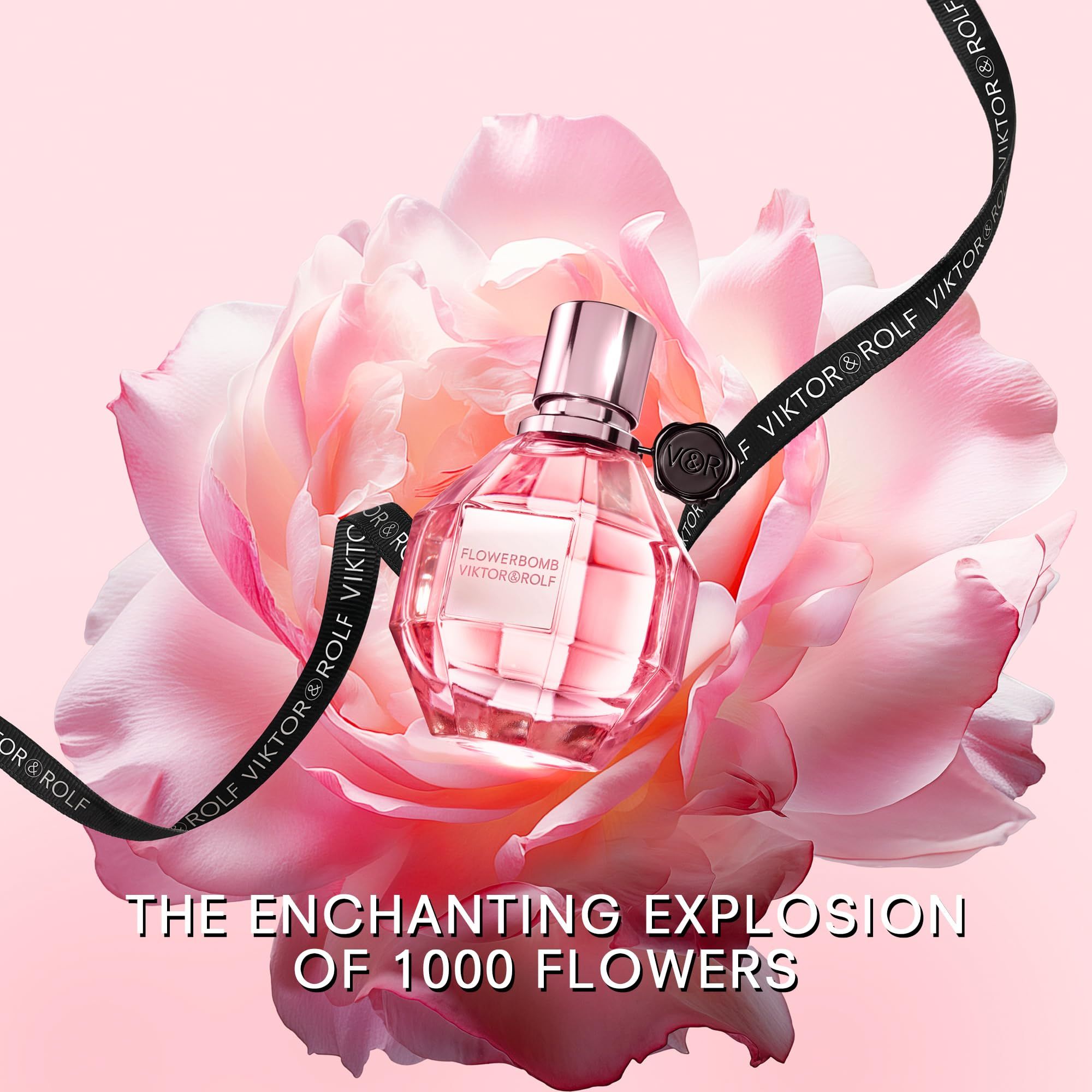 Flacon de parfum Flowerbomb de Viktor & Rolf devant une fleur rose. Ruban noir avec texte : Viktor & Rolf. Texte : The Enchanting Explosion of 1000 Flowers.