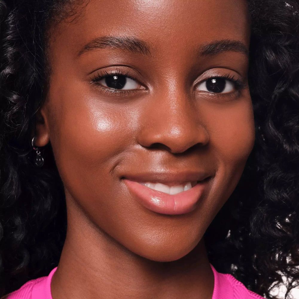 Gros plan sur un visage avec une peau brillante. La personne sourit.