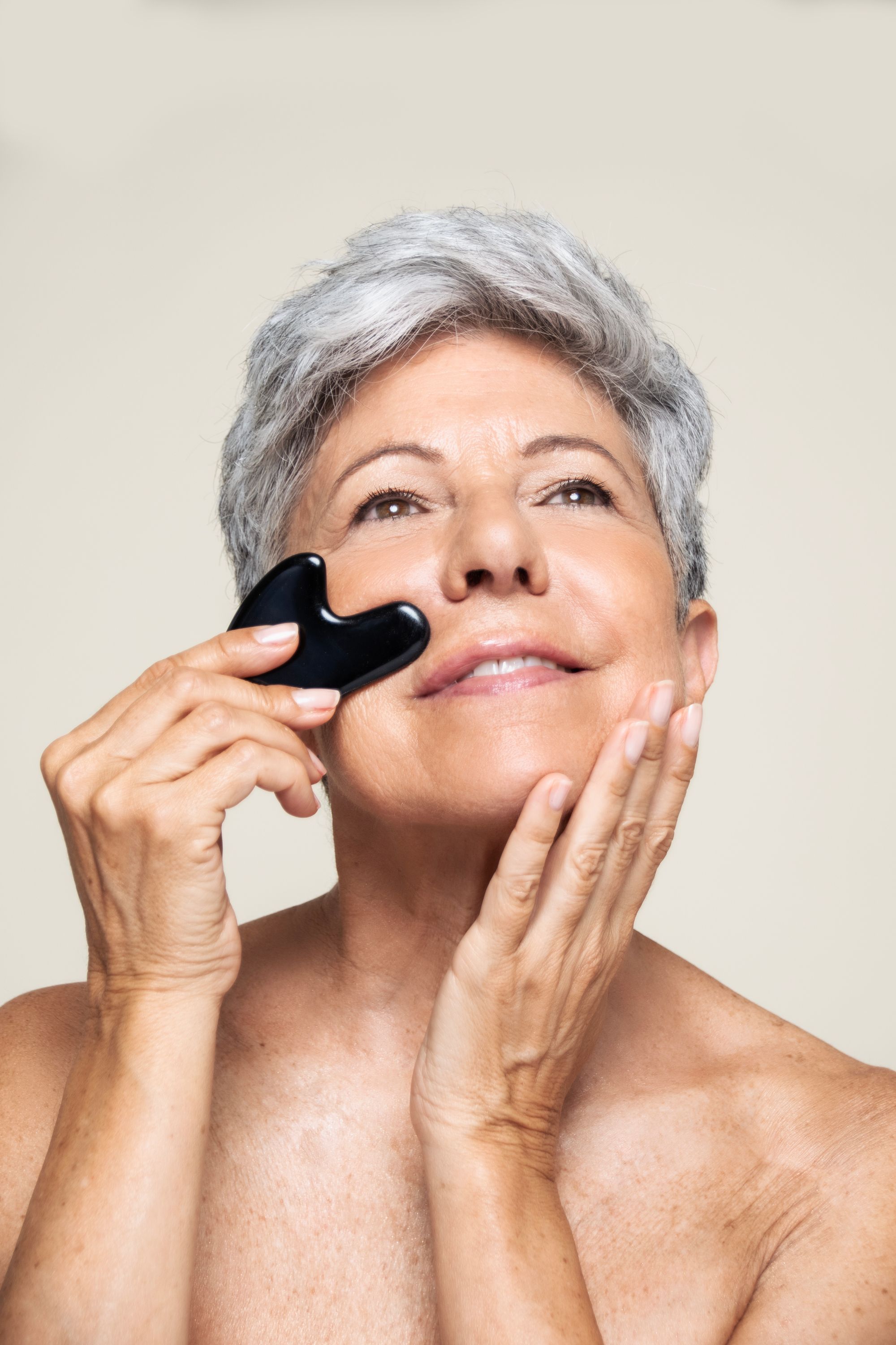 Femme utilisant un Gua Sha noir sur son visage. Contact avec la peau.