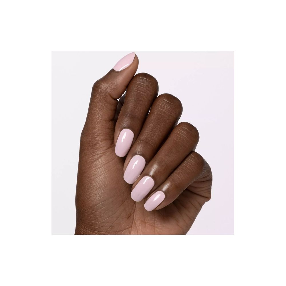Main avec ongles vernis en rose clair. Tous les ongles sont uniformément vernis.
