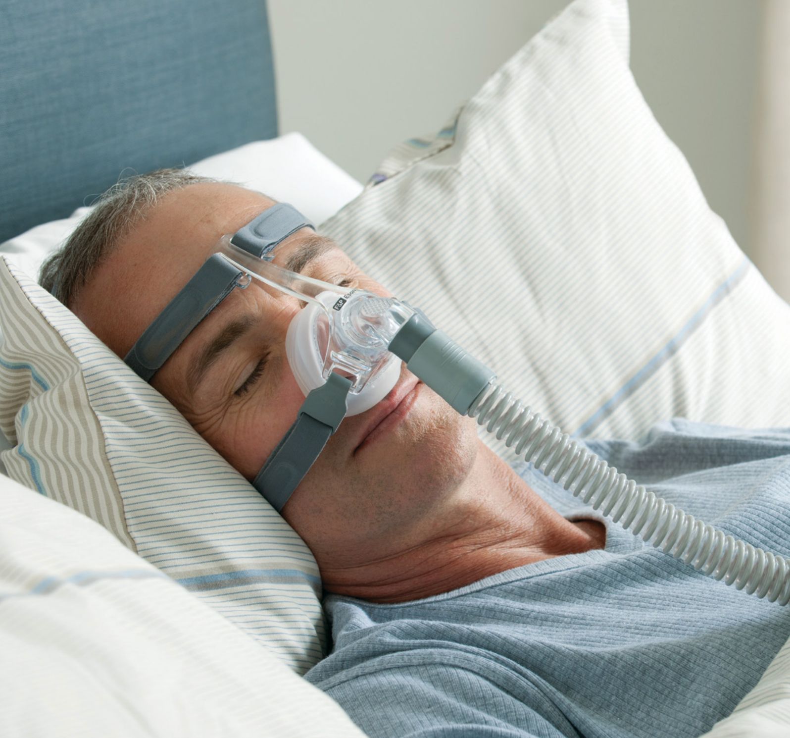 Homme dormant avec un masque nasal et un tuyau connectés.