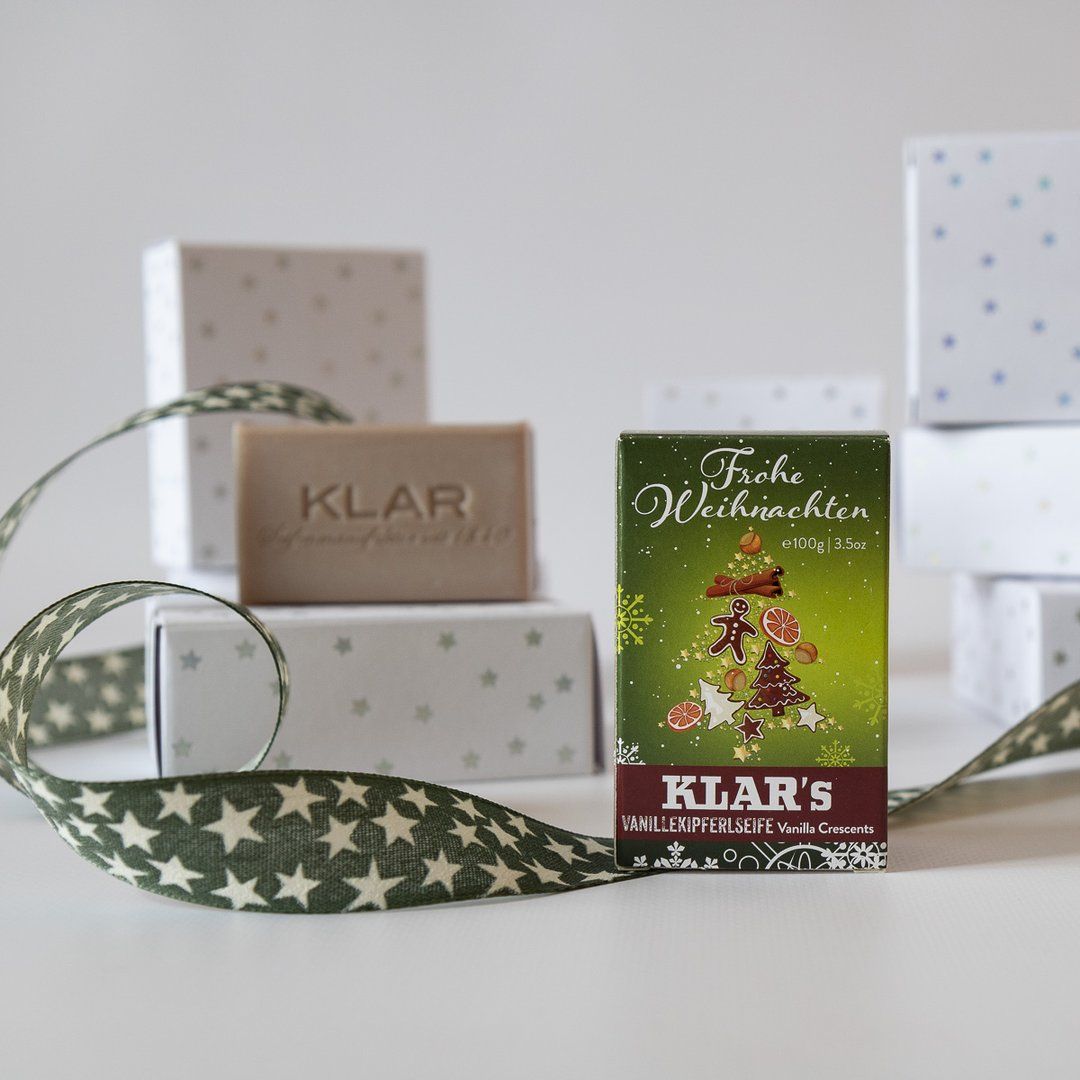 Savon et emballage avec motif sapin de Noël. Savon avec "KLAR" estampillé. Boîtes cadeaux et ruban en arrière-plan.