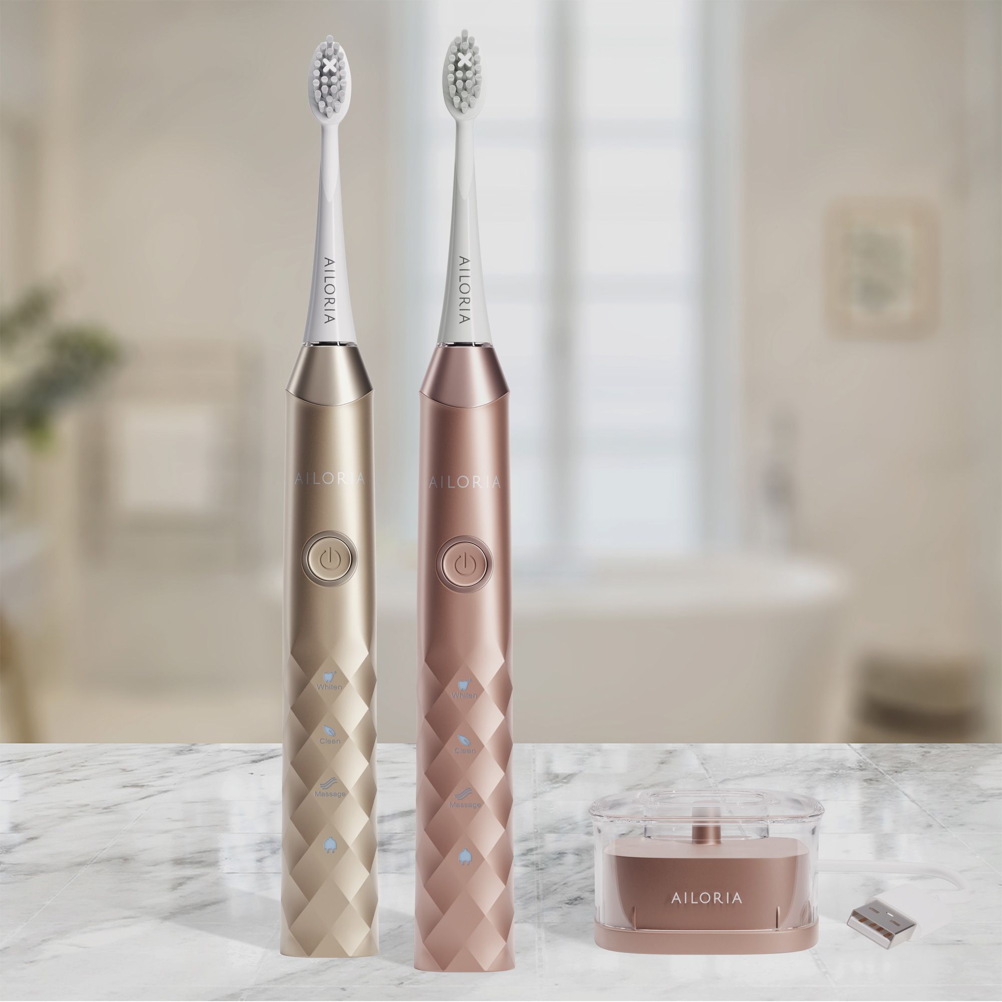 Deux brosses à dents, or et or rose. Station de charge. Logo AILORIA. Arrière-plan salle de bain.
