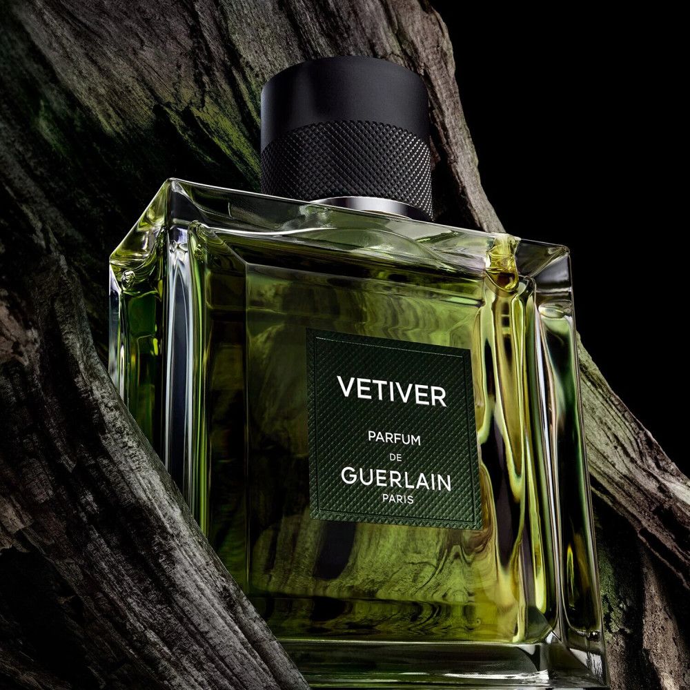 Flacon en verre avec liquide verdâtre. Bouchon noir. Étiquette "VETIVER PARFUM de GUERLAIN PARIS".